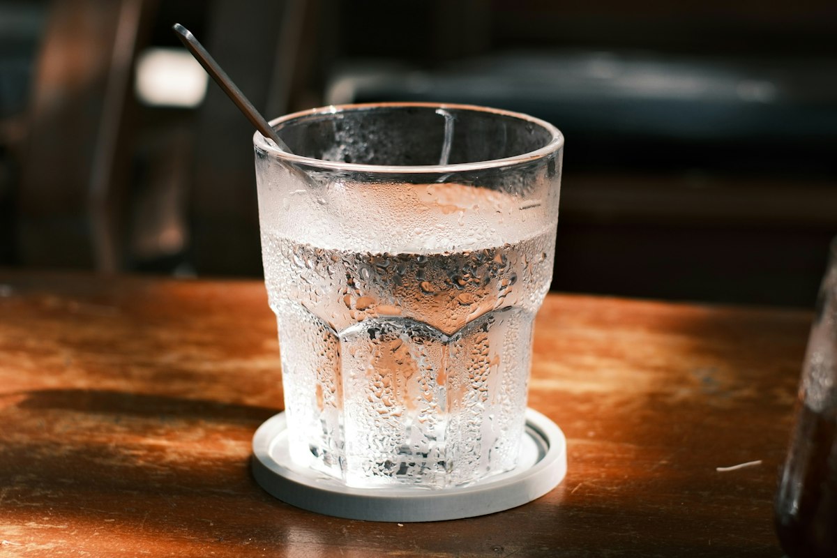 Ein Glas Wasser mit Kondenswasser auf einem Holztisch