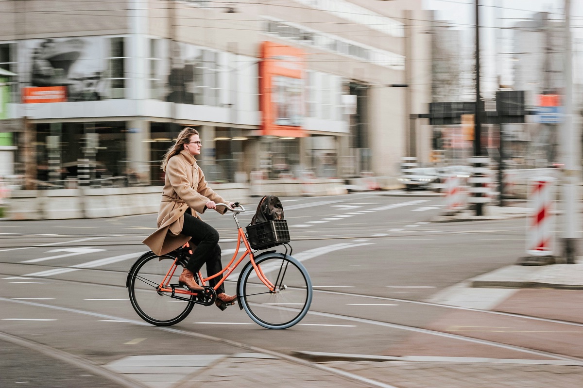 Eine Frau im Mantel fährt mit dem Fahrrad über eine Kreuzung in der Stadt