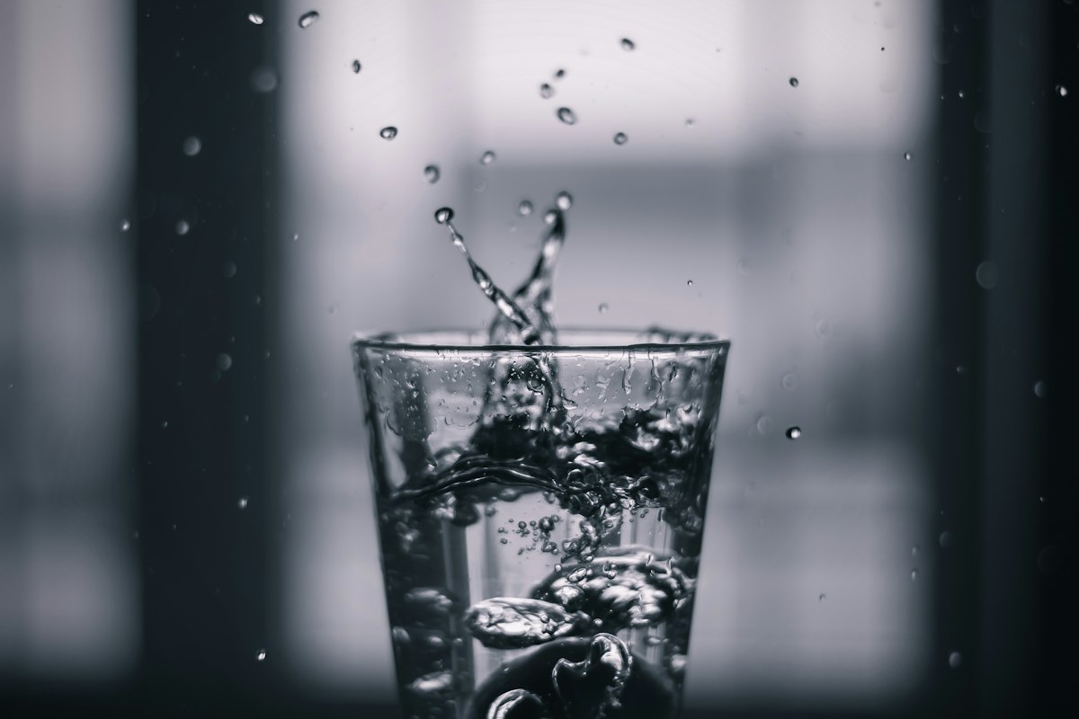 Wasser spritzt beim Einschenken in ein Glas, Schwarzweißfoto