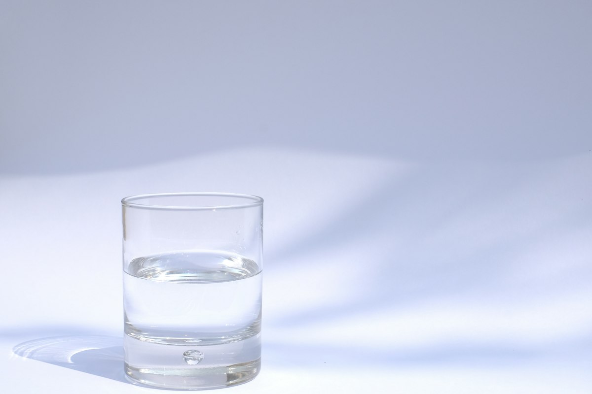 Ein klares Trinkglas mit Wasser auf hellem Untergrund