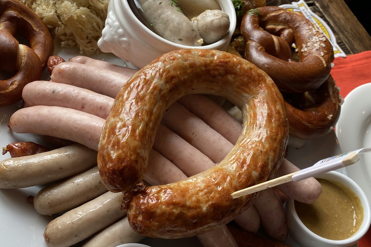 Weißwürste, eine Bratwurstschnecke, Brezeln, Sauerkraut und süßer Senf auf einer Platte