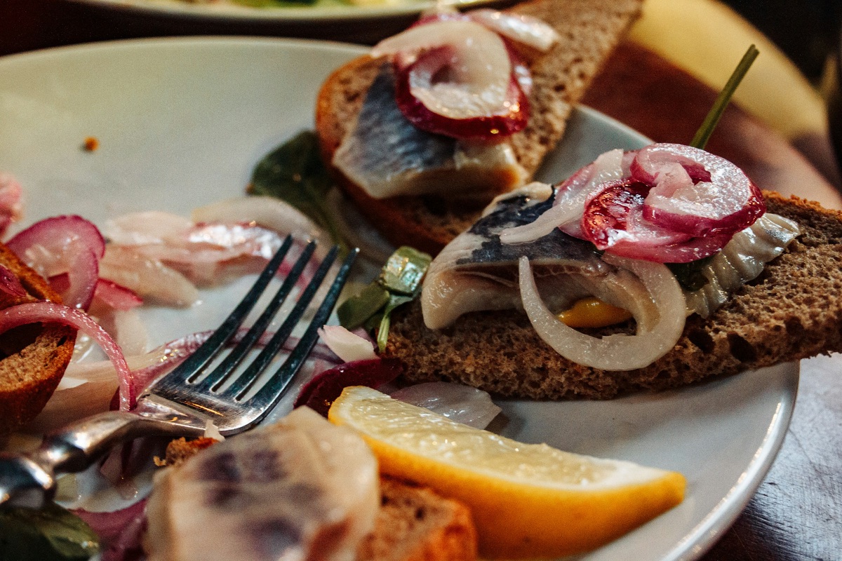 Hering mit roten Zwiebelringen auf dunklem Brot